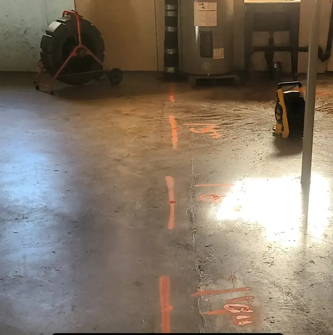 Un déboucheur de canalisations est posé sur le sol d'une pièce.