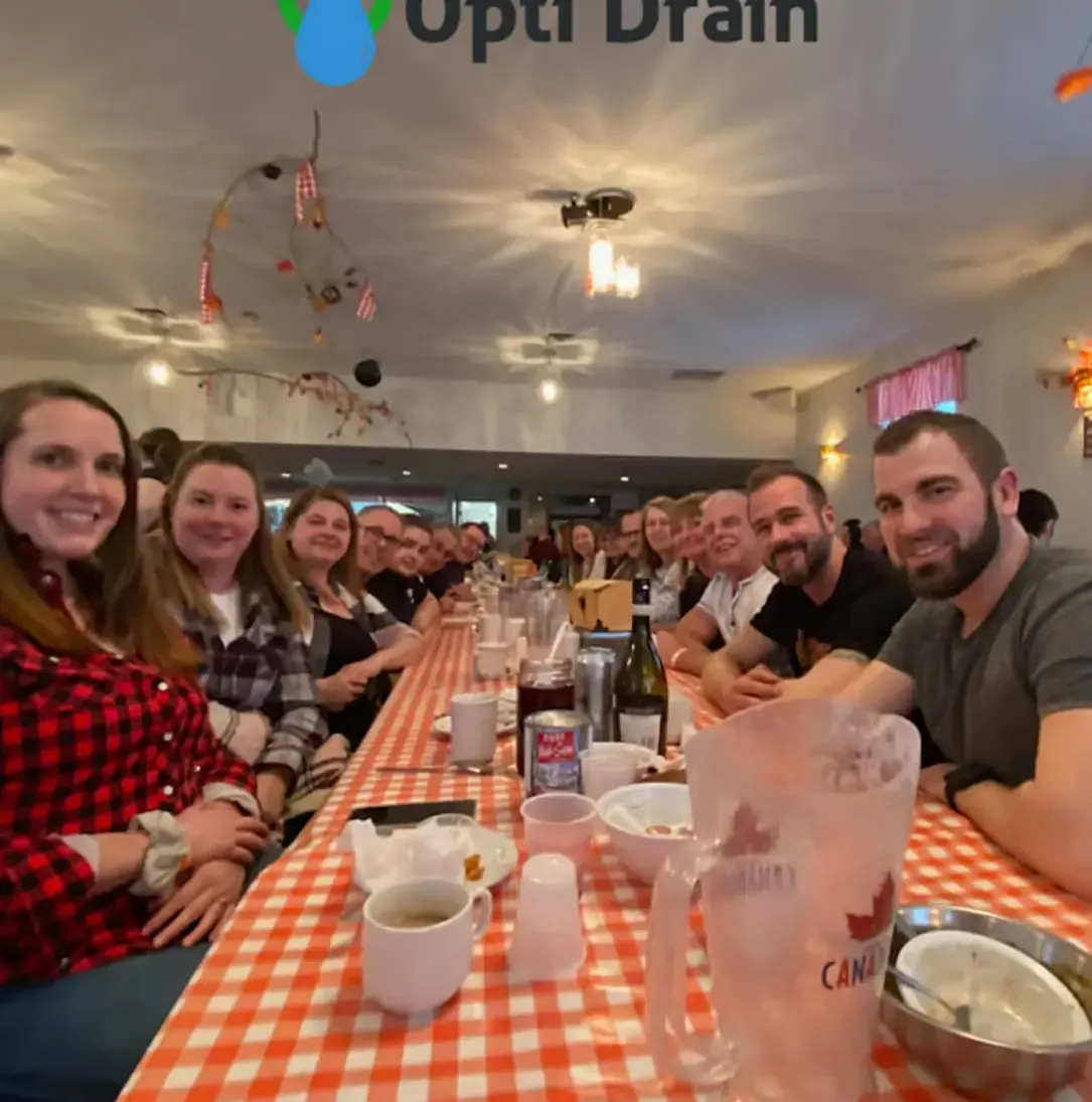 Un groupe de personnes est assis à une longue table avec un pichet sur lequel est écrit « Canada »