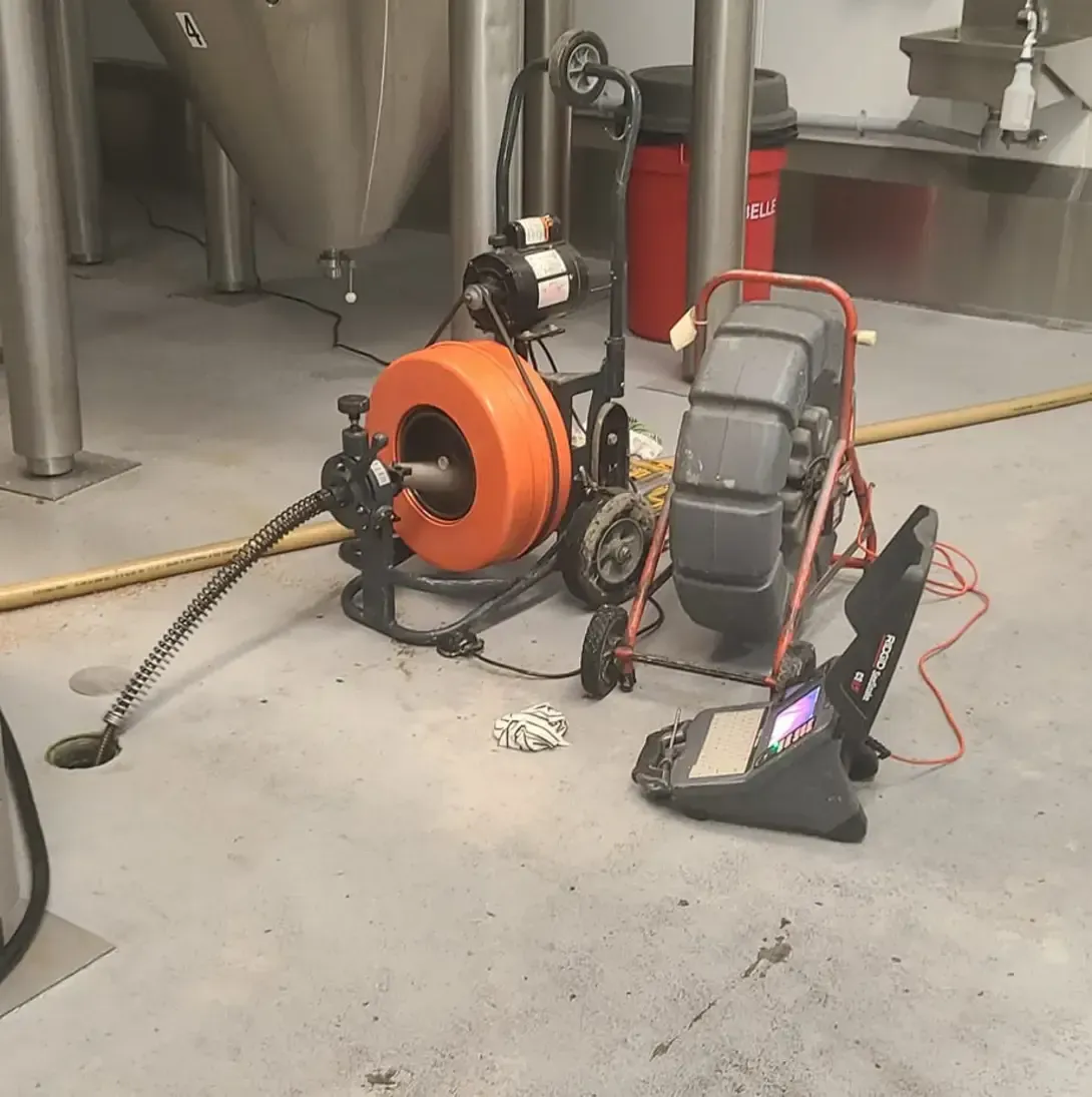 Un déboucheur de canalisations est assis sur le sol à côté d'une caméra