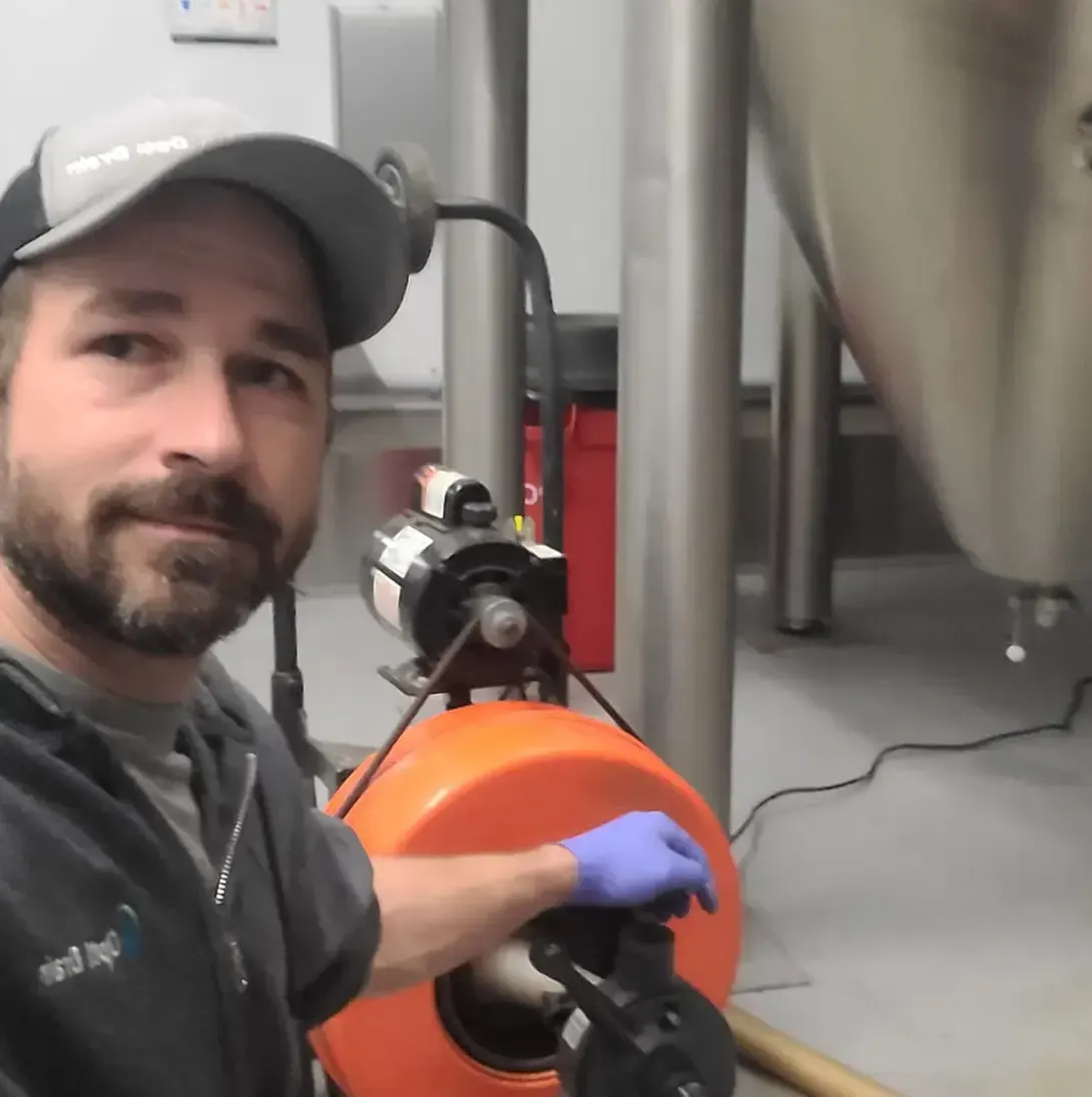 Un homme portant un chapeau et des gants tient un tuyau orange