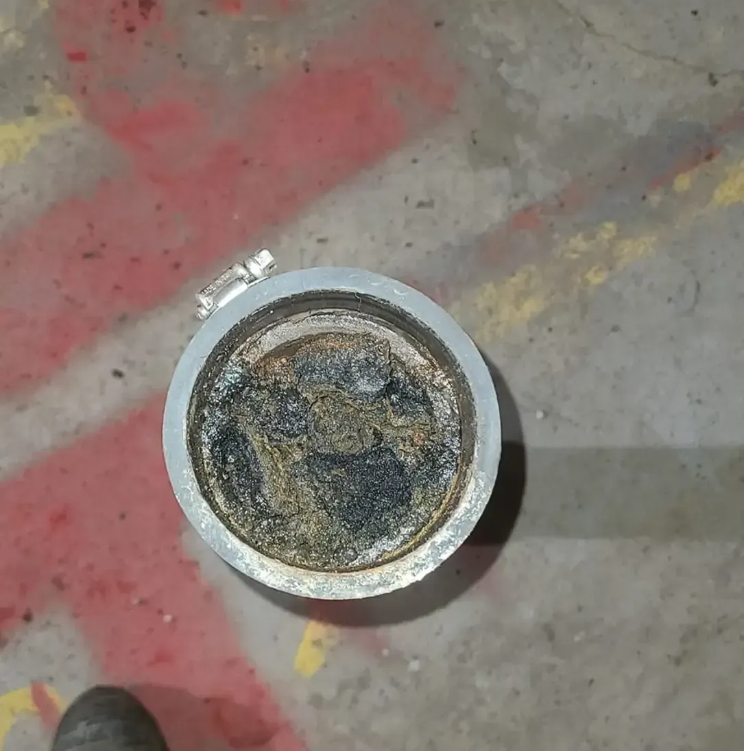 Un objet métallique sale est posé sur un sol en béton.