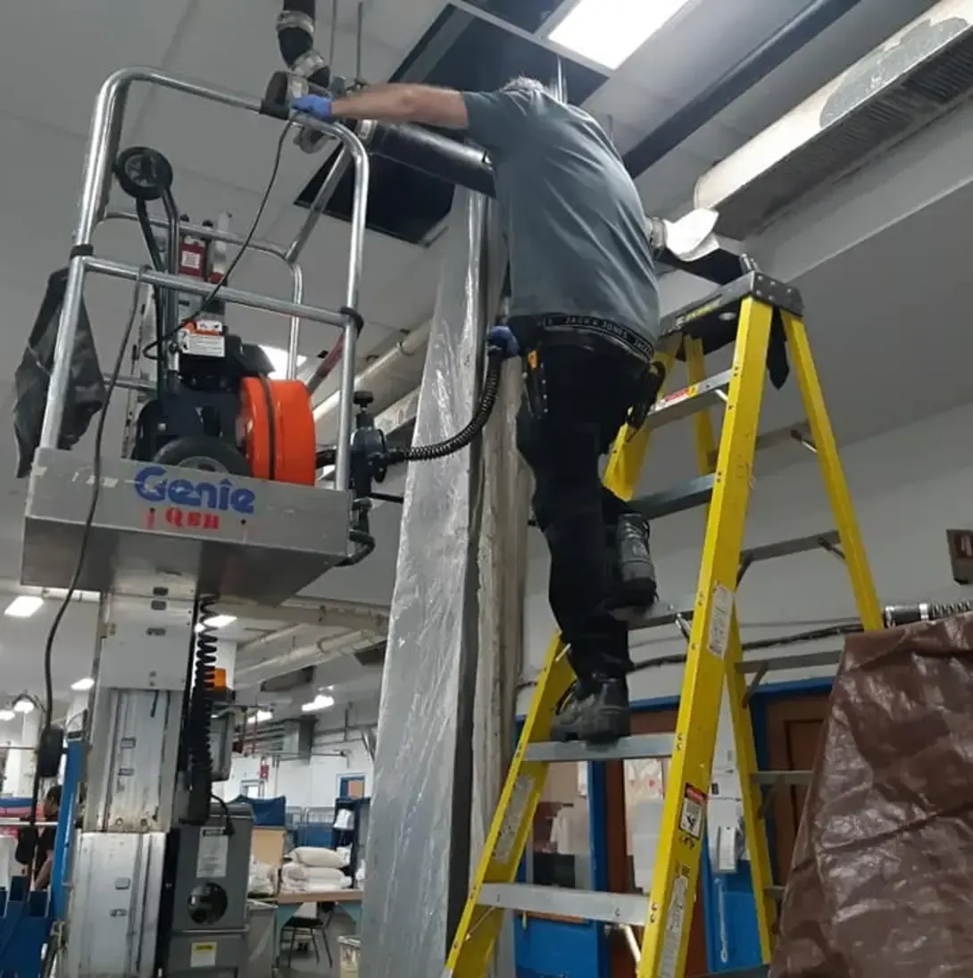 Un homme se tient sur une échelle devant une machine à génie