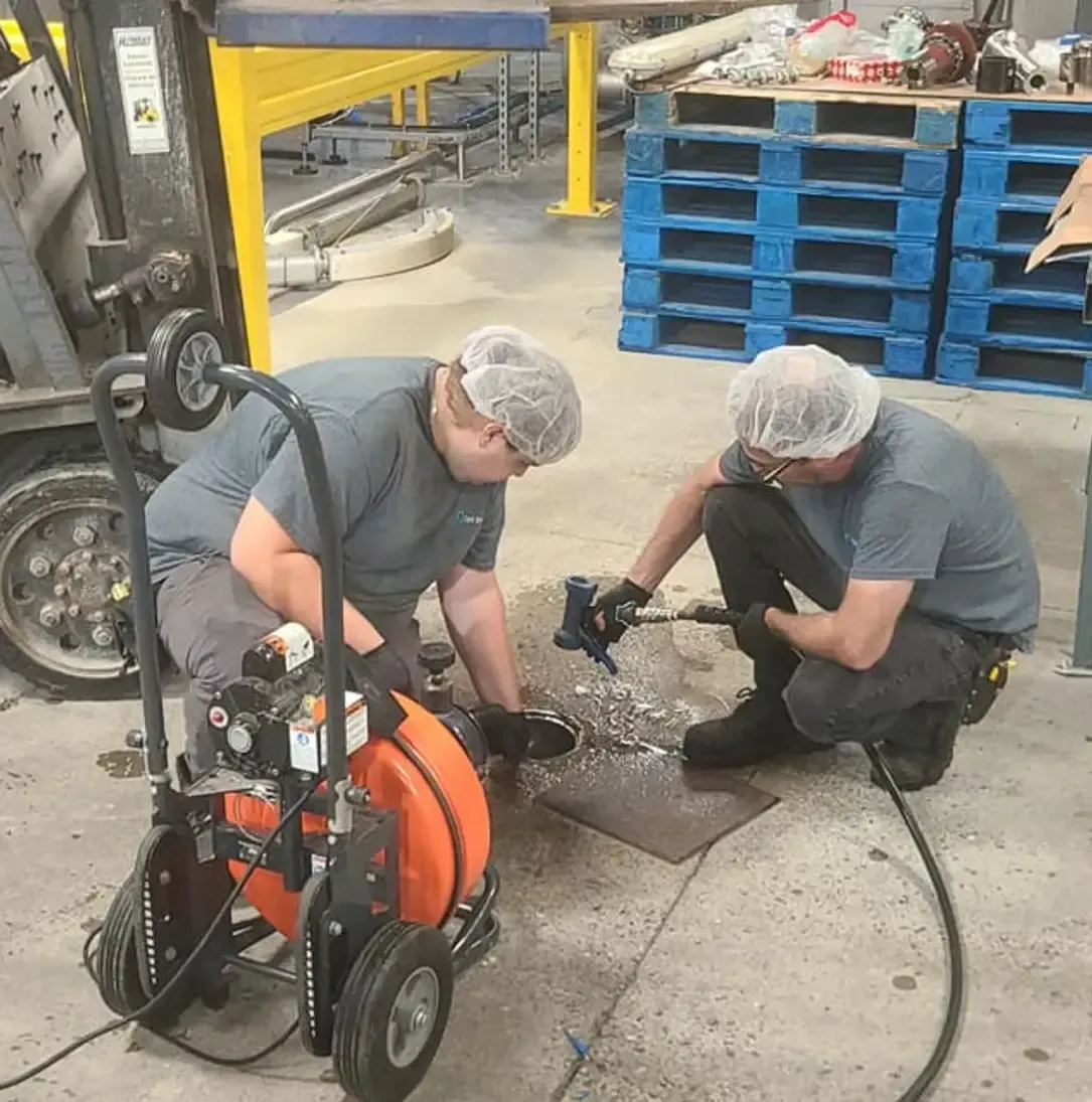 Deux hommes travaillent sur une machine dans une usine.