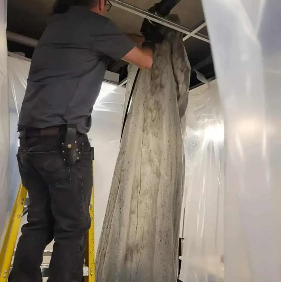 Un homme sur une échelle travaille sur un morceau de bois