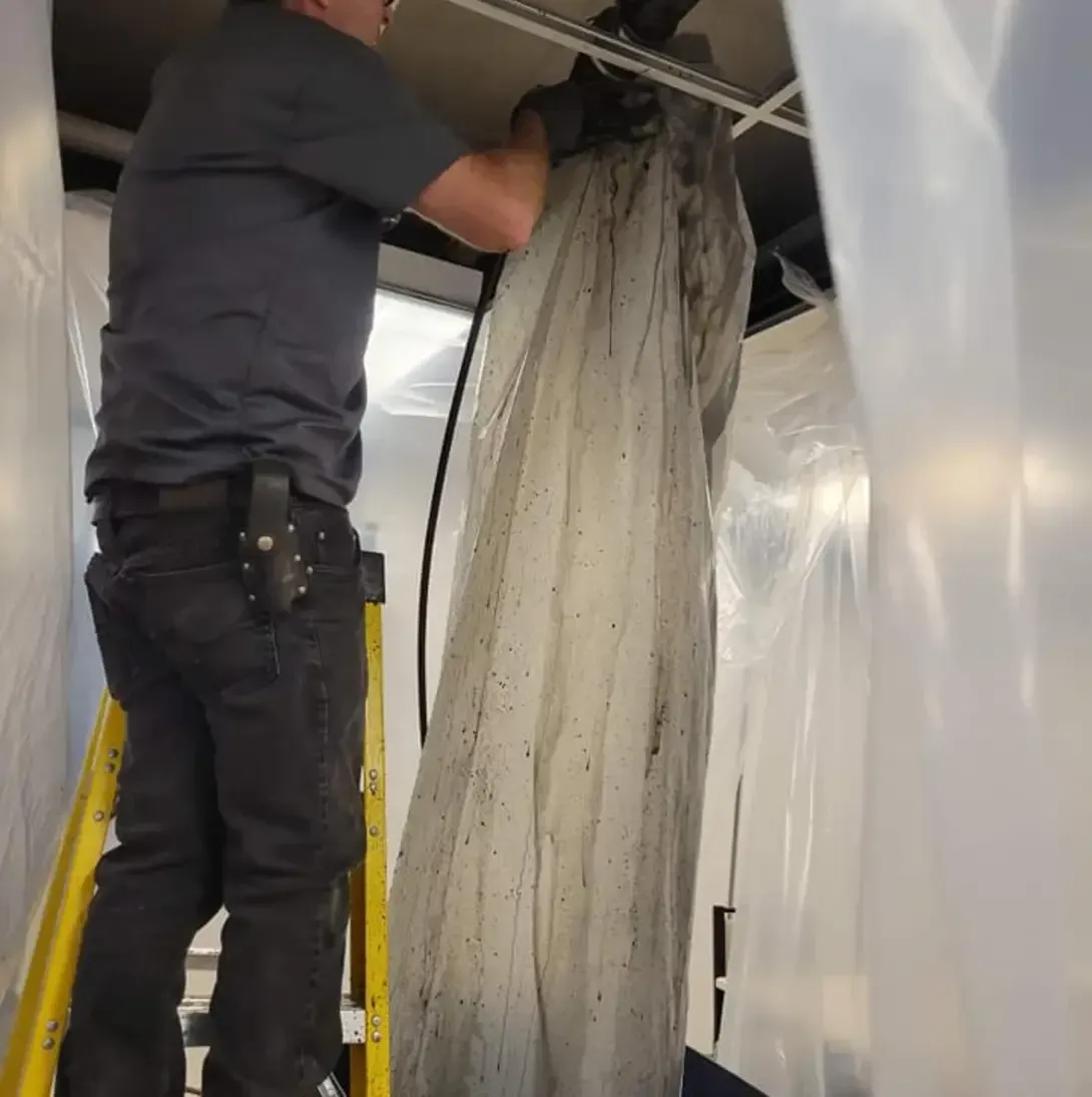 Un homme sur une échelle travaille sur un morceau de plastique