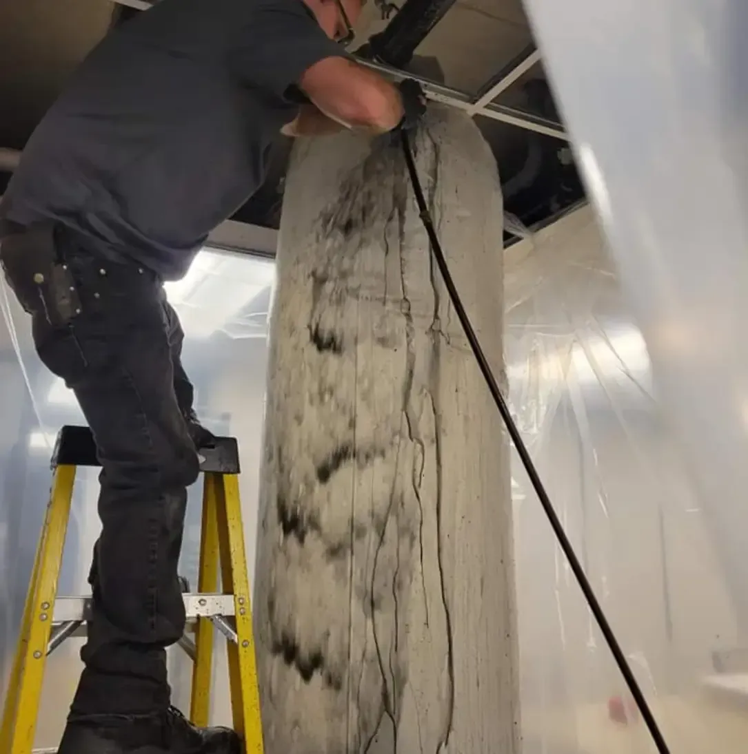 Un homme sur une échelle travaille sur un grand morceau de bois