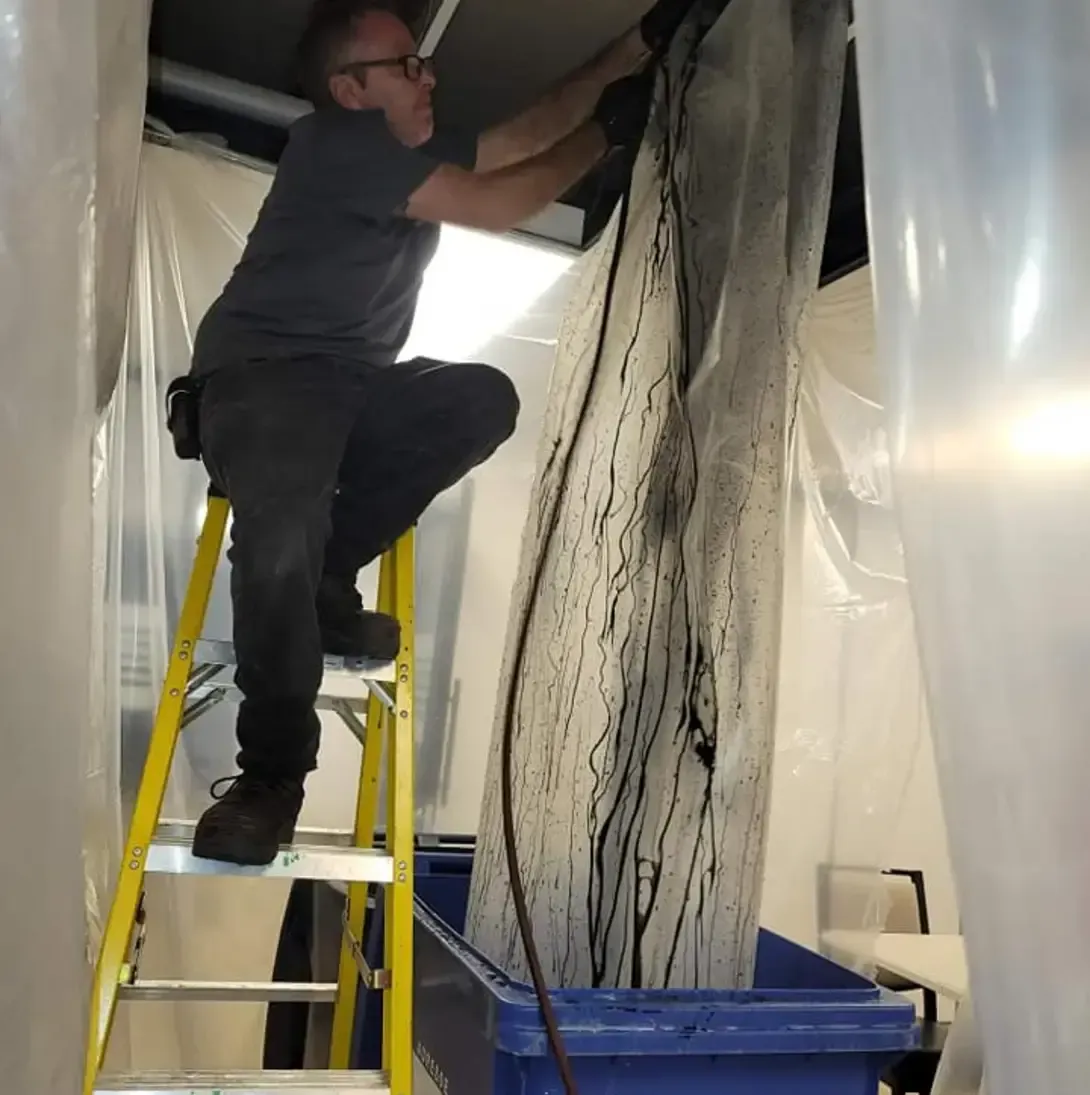 Un homme sur une échelle travaille sur un mur