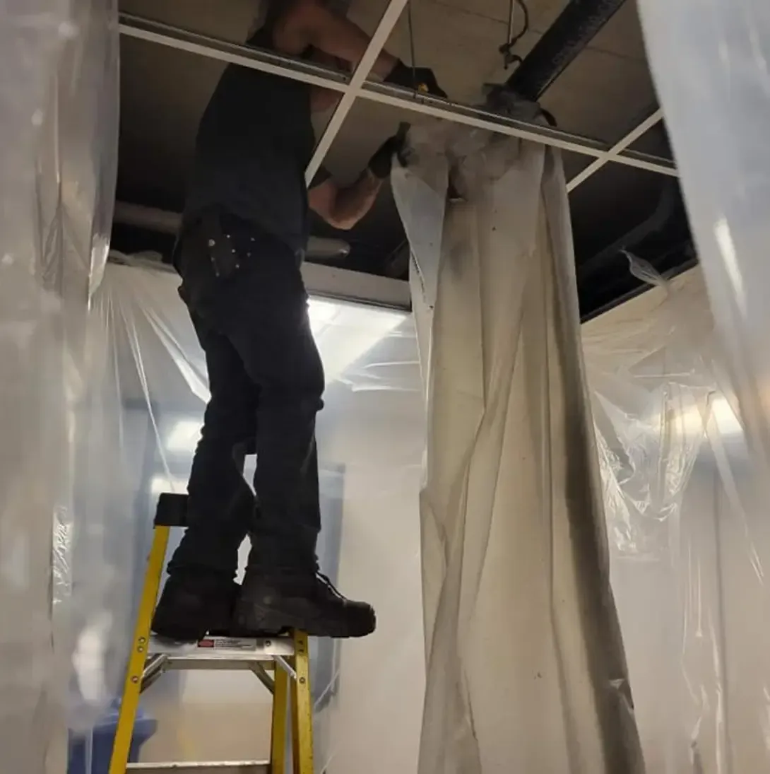 Un homme debout sur une échelle travaillant sur un plafond