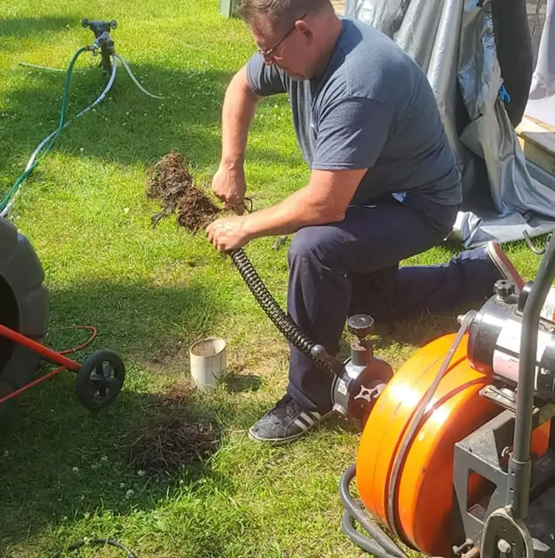 Un homme est agenouillé dans l'herbe avec un tuyau.