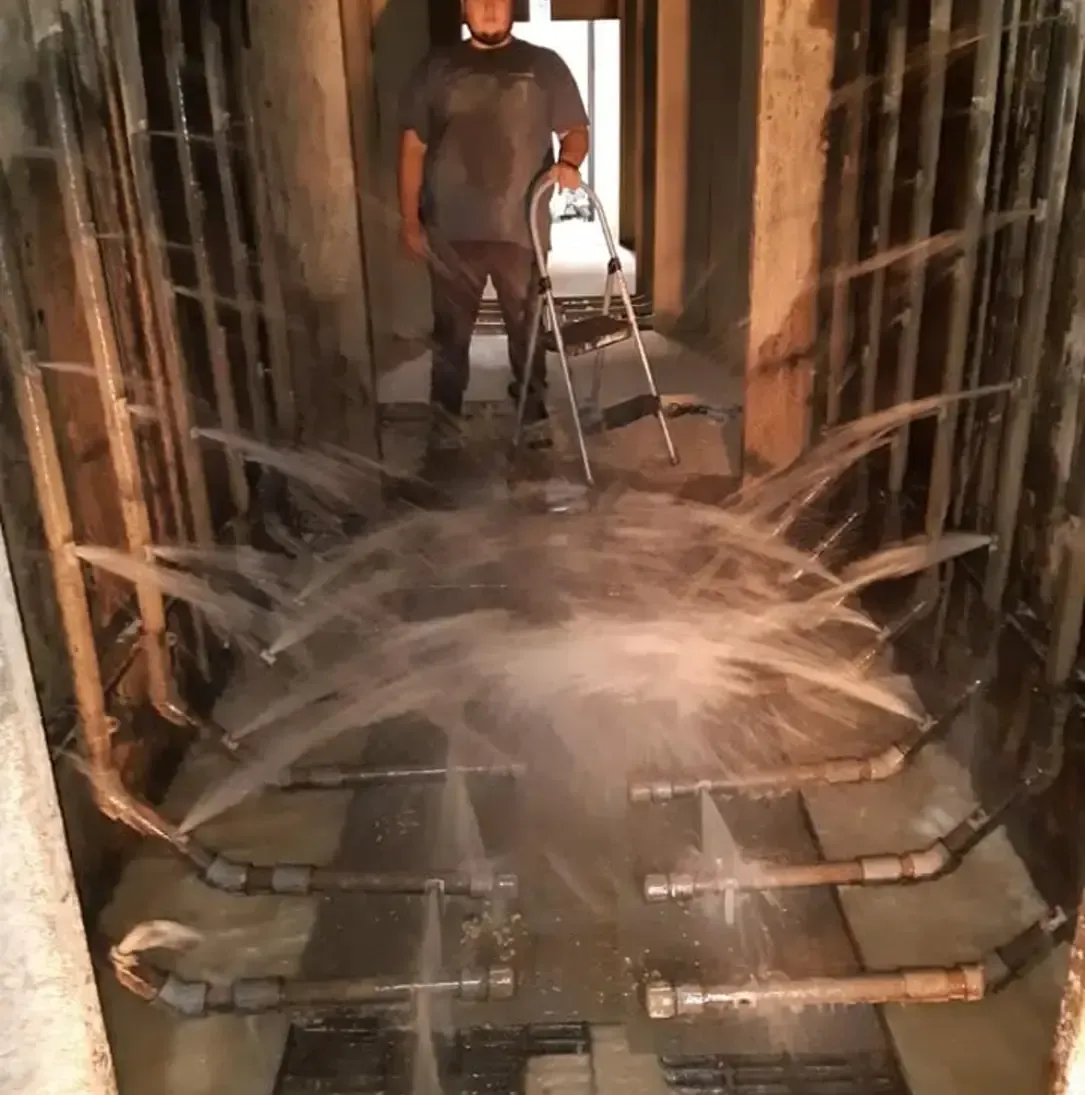 Un homme se tient debout dans une pièce avec de l'eau sortant des tuyaux