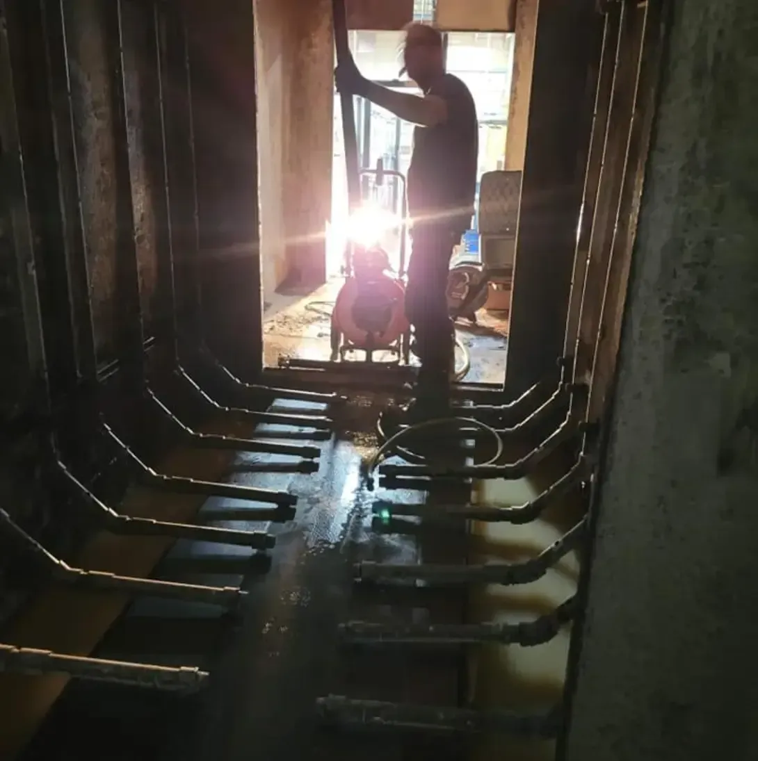 Un homme en chemise noire se tient dans une pièce sombre