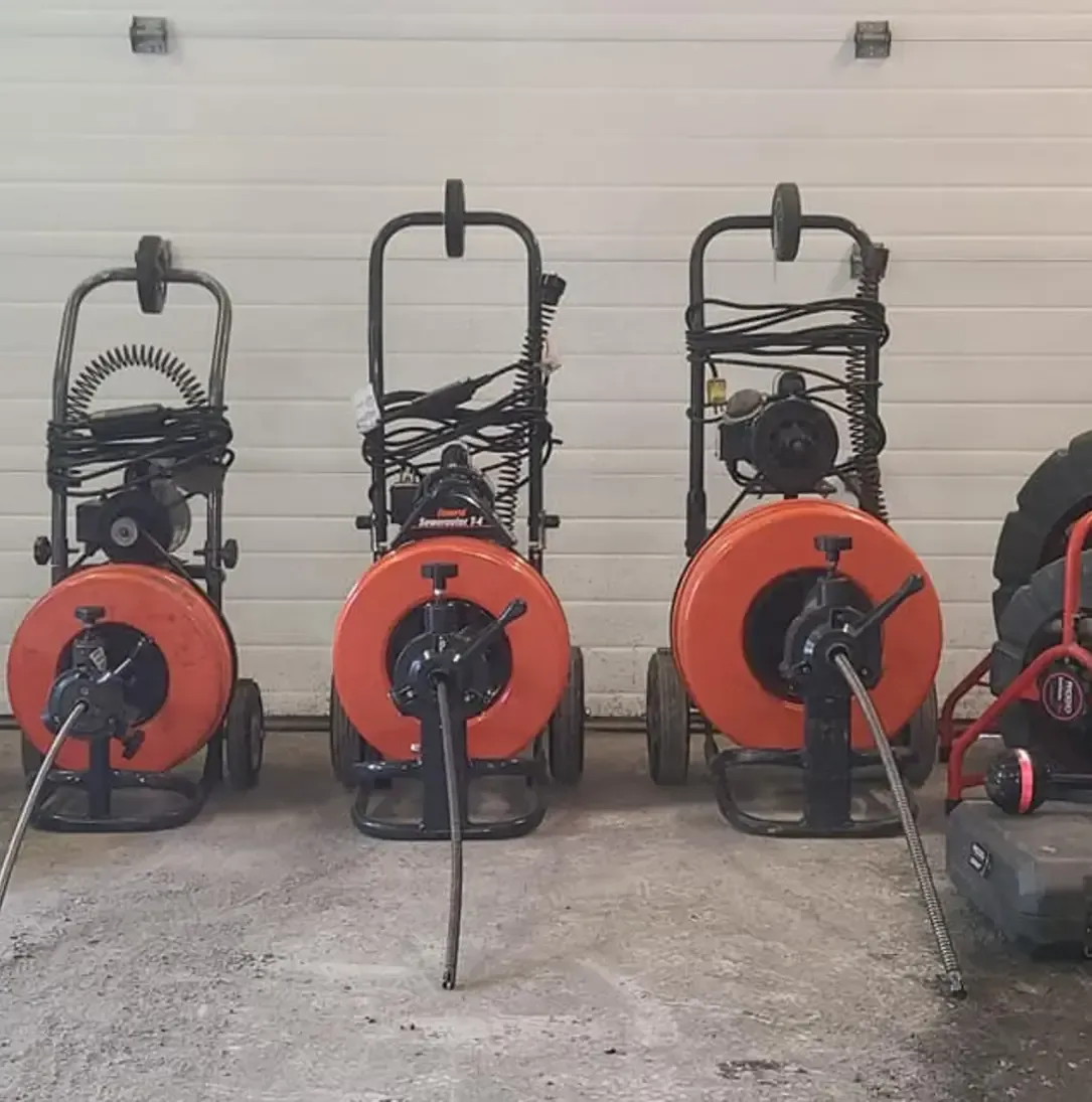 Trois nettoyeurs de canalisations sont alignés dans un garage.