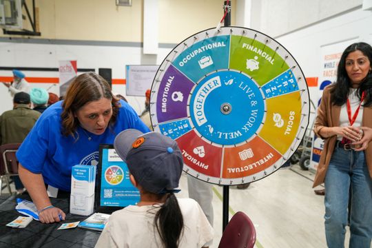 Punjabi Health Fair April 21st, 2024. A woman is standing next to a child in front of a spinning wheel. 