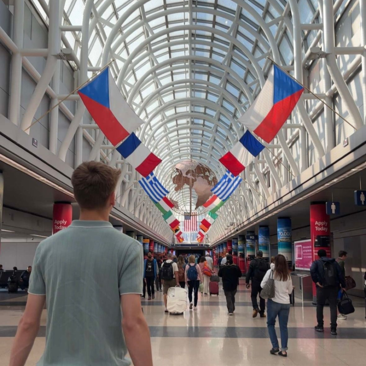 A dock with two benches extends into a dark lake under a cloudy sky.