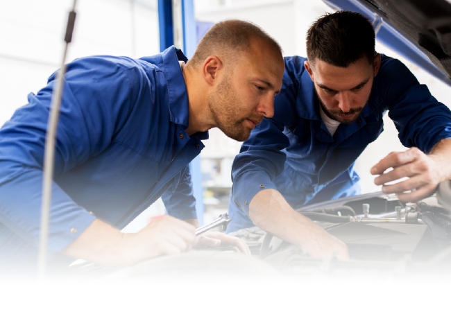 Two mechanics are working on a car in a garage.