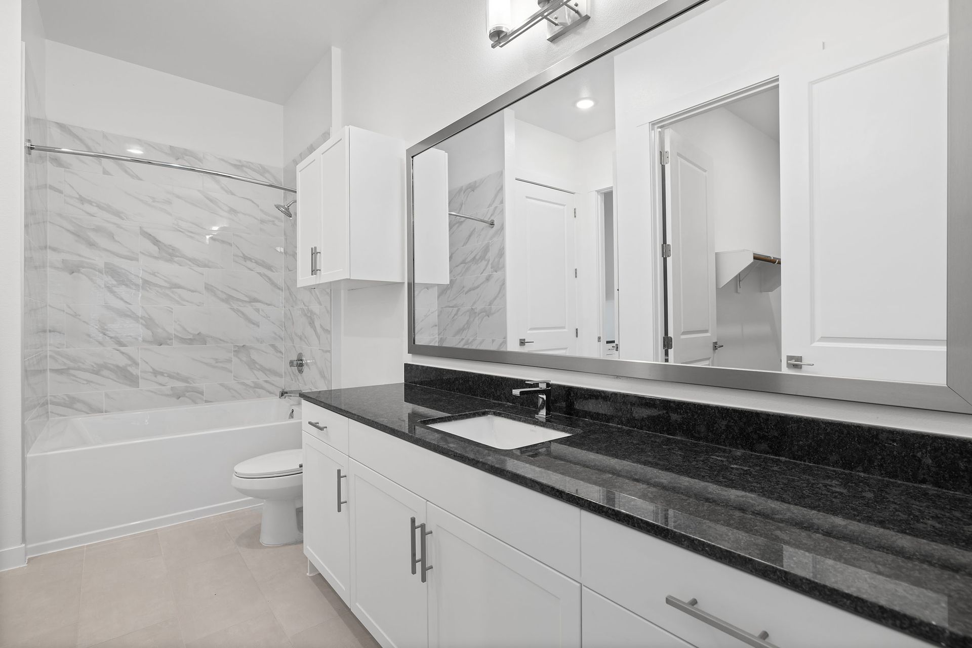 A bathroom with two sinks, a toilet, and a modern bath/shower at The Everett, offering apartments for rent in Northwest Austin, TX