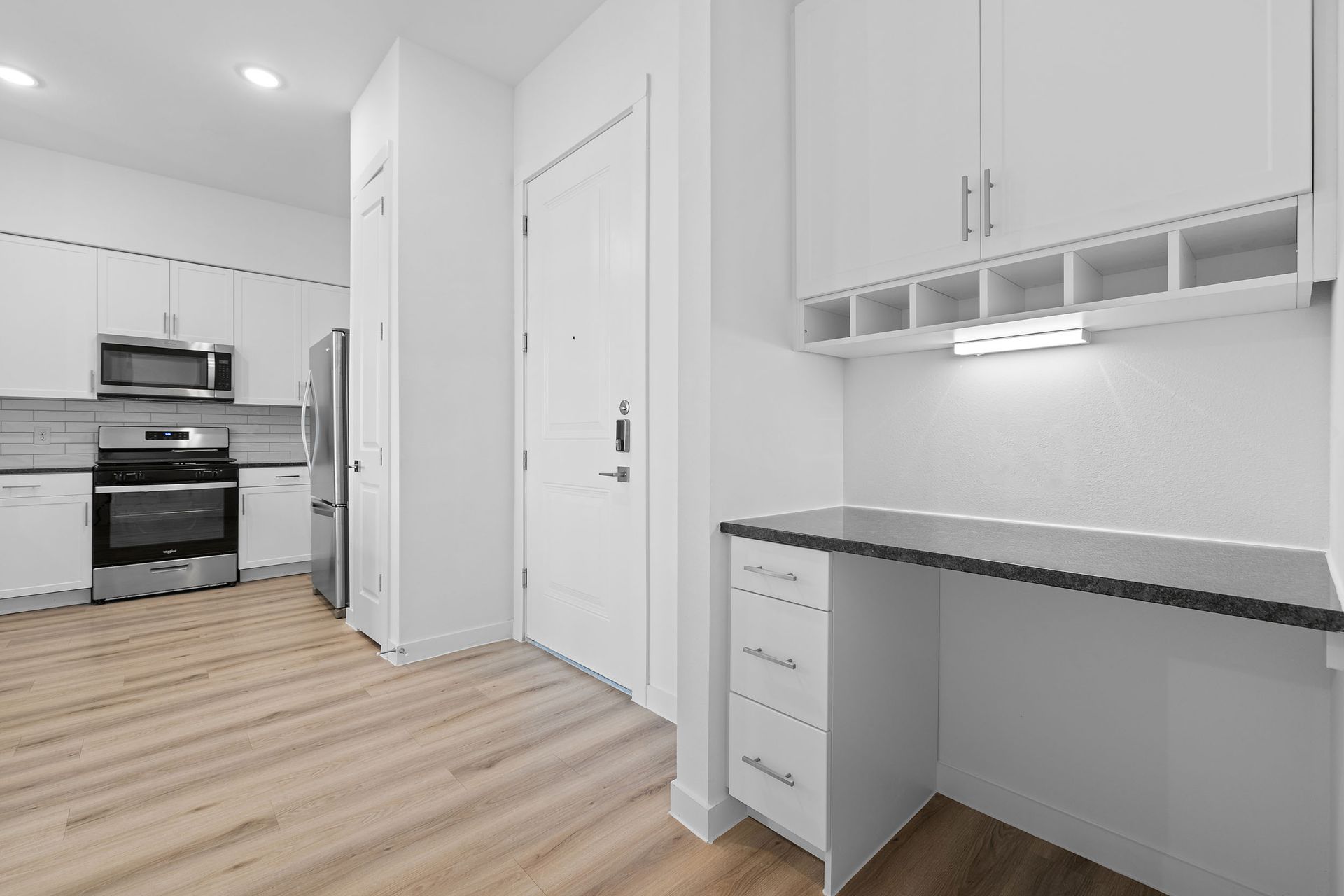 A kitchen with white cabinets and stainless steel appliances and eatra space with a desk at The Everett, offering apartments for rent in Northwest Austin, TX