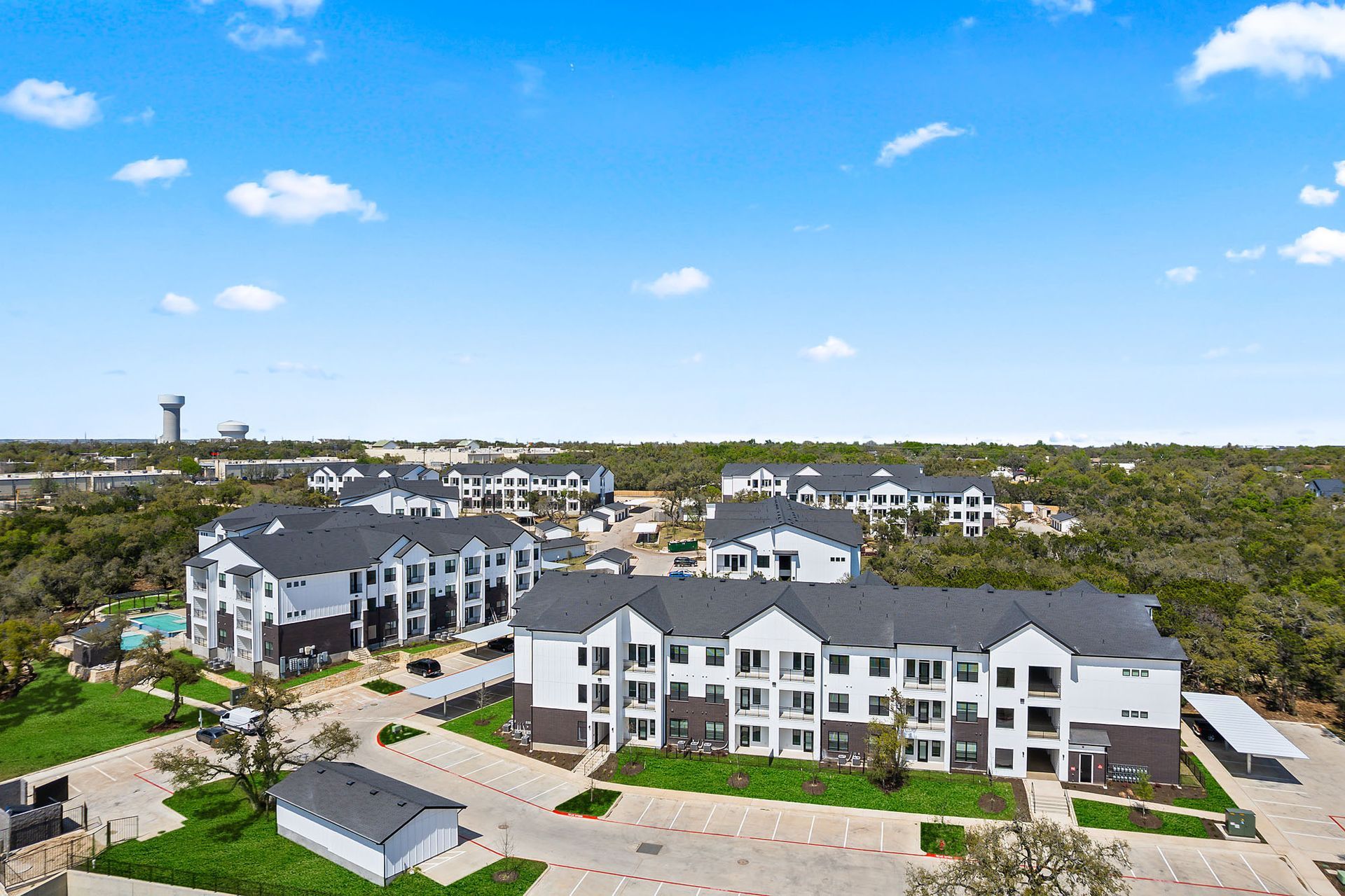 An aerial view of a large brand new apartment building surrounded by trees and a parking lot at The Everett, offering apartments for rent in Austin, TX.