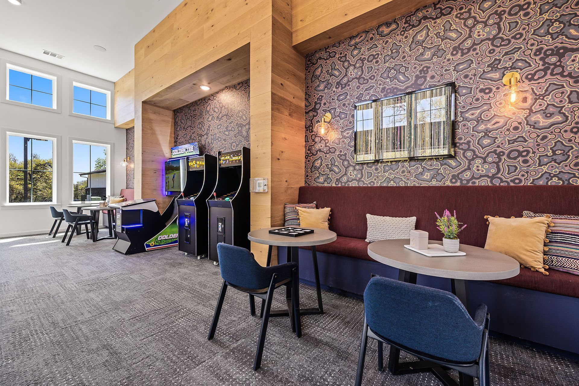 Apartment game room with tables and chairs and arcade games at The Everett, offering apartments in Round Rock ISD.
