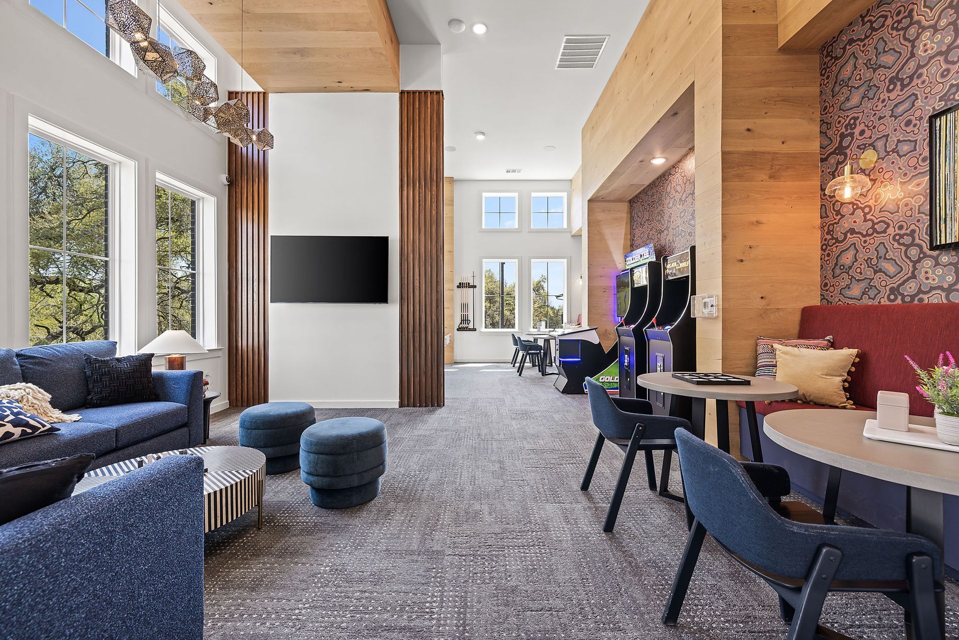 A game room with a couch, chairs, tables, and a flat screen TV at The Everett, offering apartments near Lake Travis.