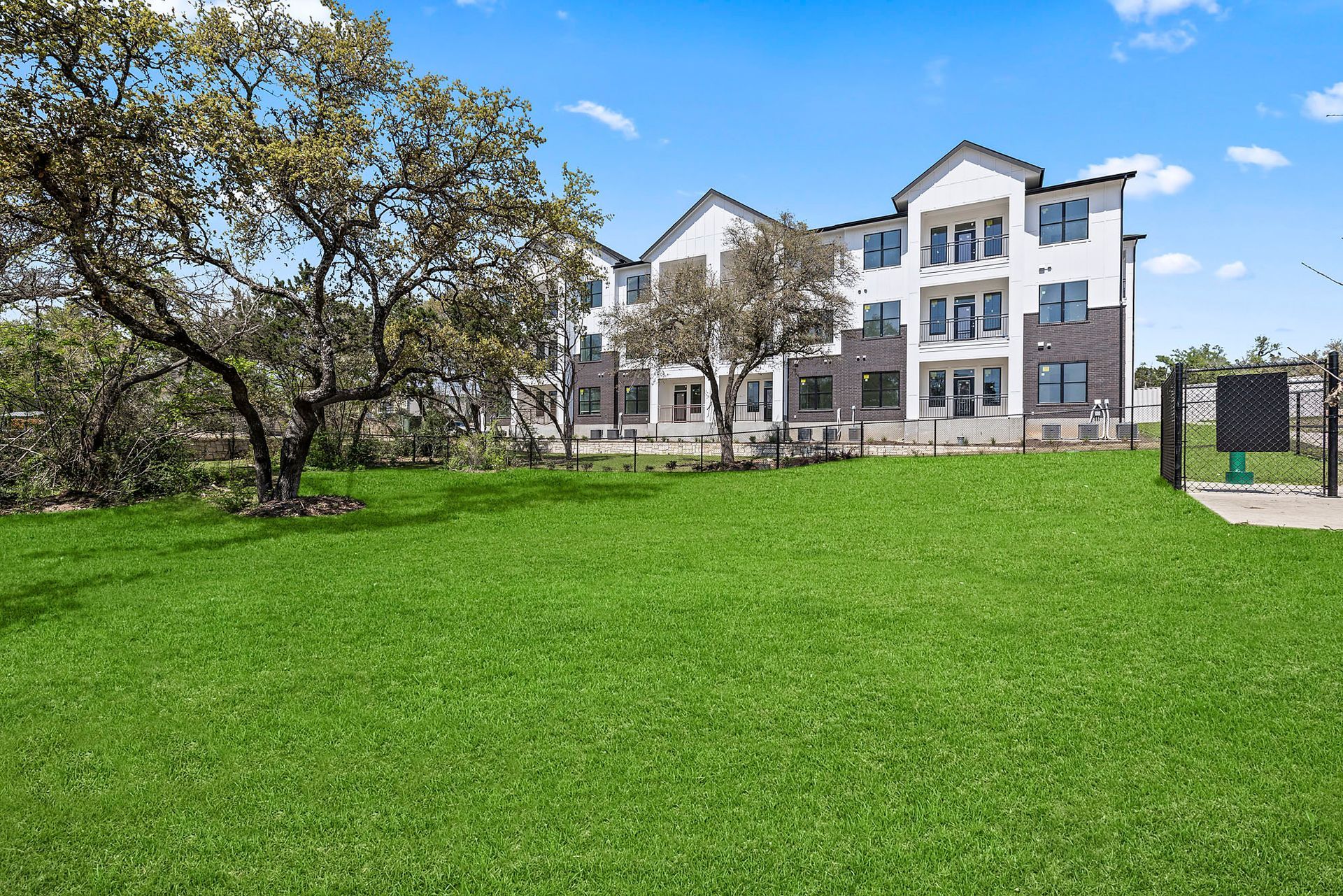 A large building with a lot of grass and a pet park in front of it at The Everett, offering apartments near The Domain, Austin, TX.