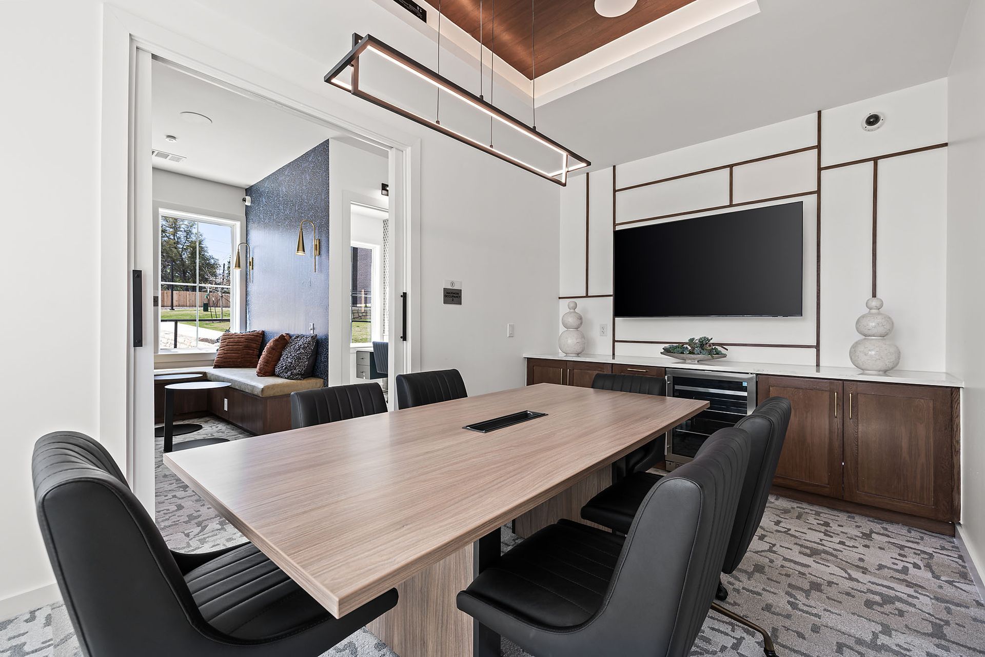 A conference room with a long table and chairs and a flat screen TV at The Everett, offering North Austin apartments for rent.