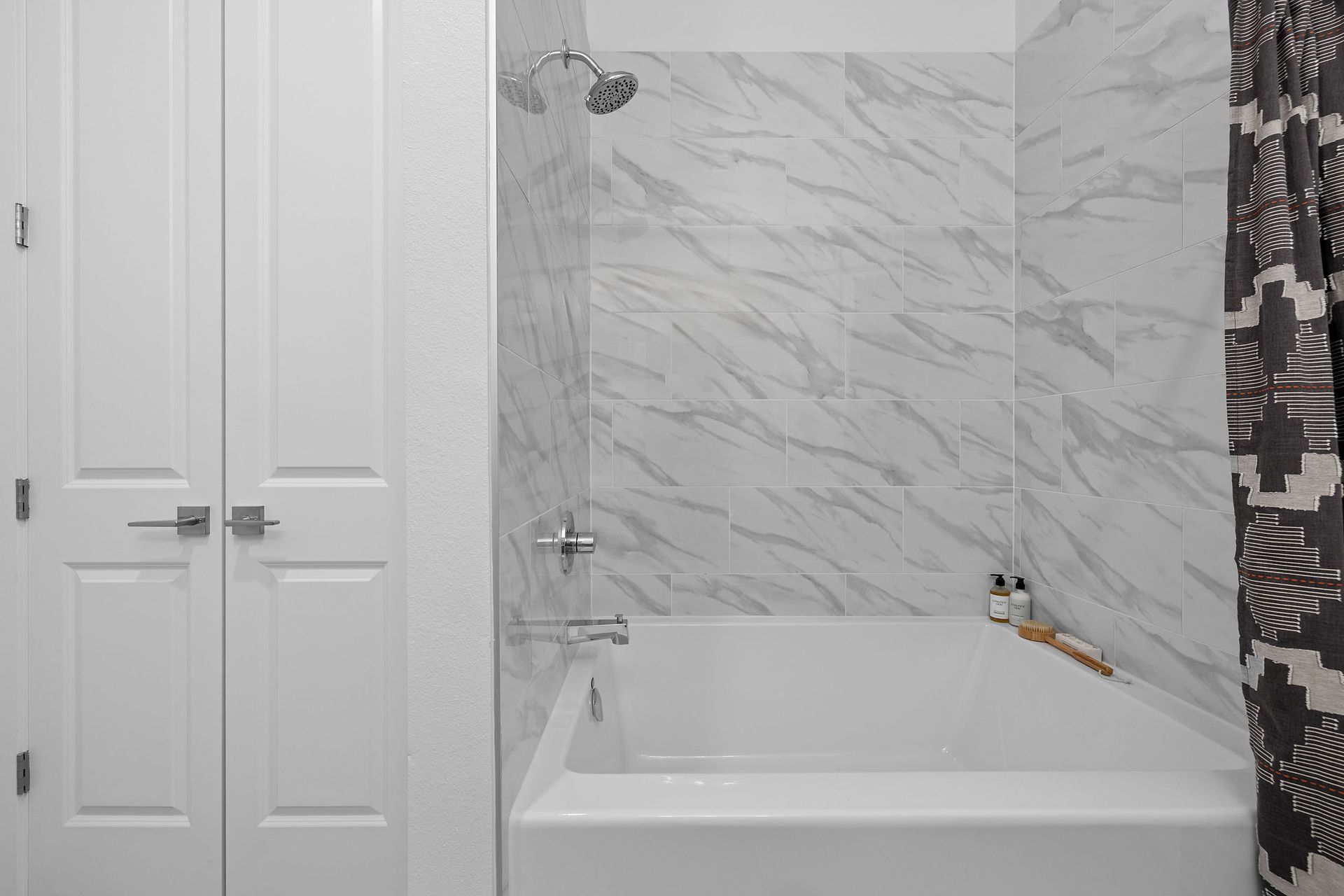 A luxury bathroom with a bathtub , shower, marble backsplash and closet at The Everett, offering apartments for rent in Northwest Austin, TX