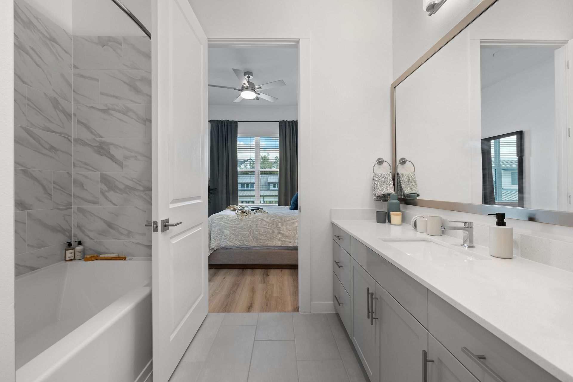 An in-unit bathroom with two sinks , a tub and a mirror leading back to the spacious bedroom at The Everett, offering apartments for rent in Northwest Austin, TX.