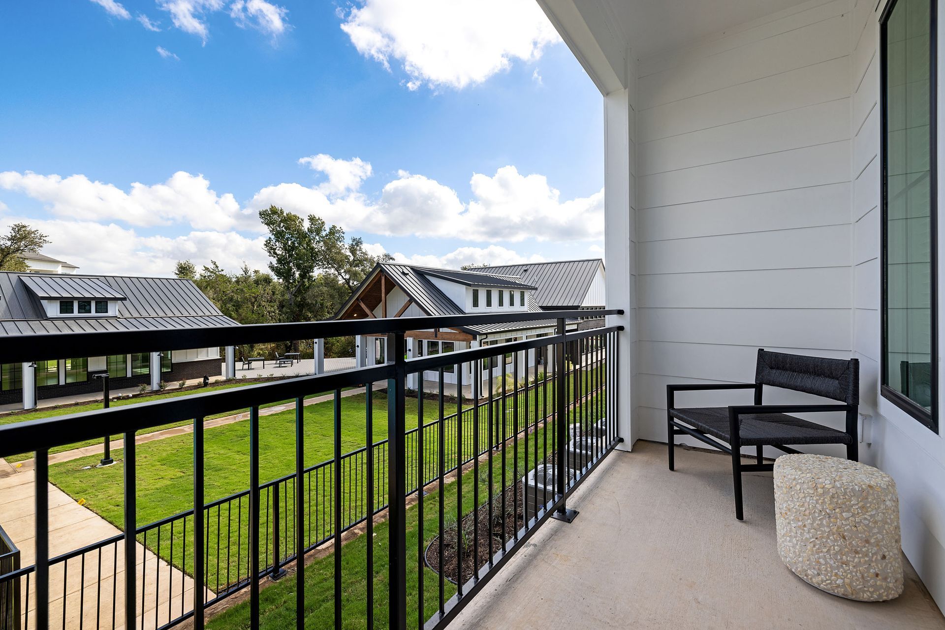 A balcony with a black railing and a chair overseeing the green lawn at The Everett, offering apartments for rent in Northwest Austin, TX