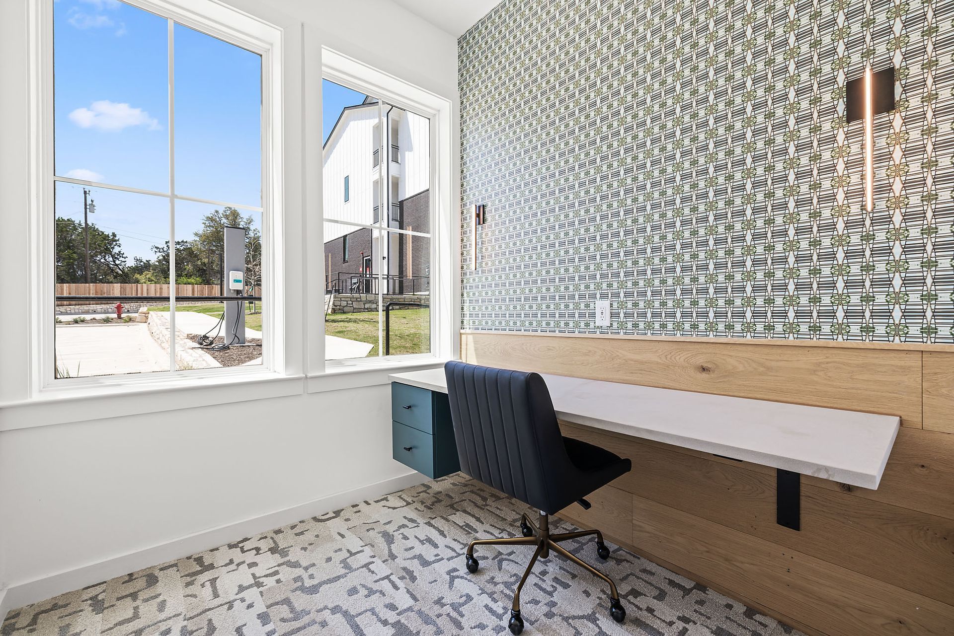 Business center room with a desk and chair in the room with a large window at The Everett, offering apartments in North Austin.