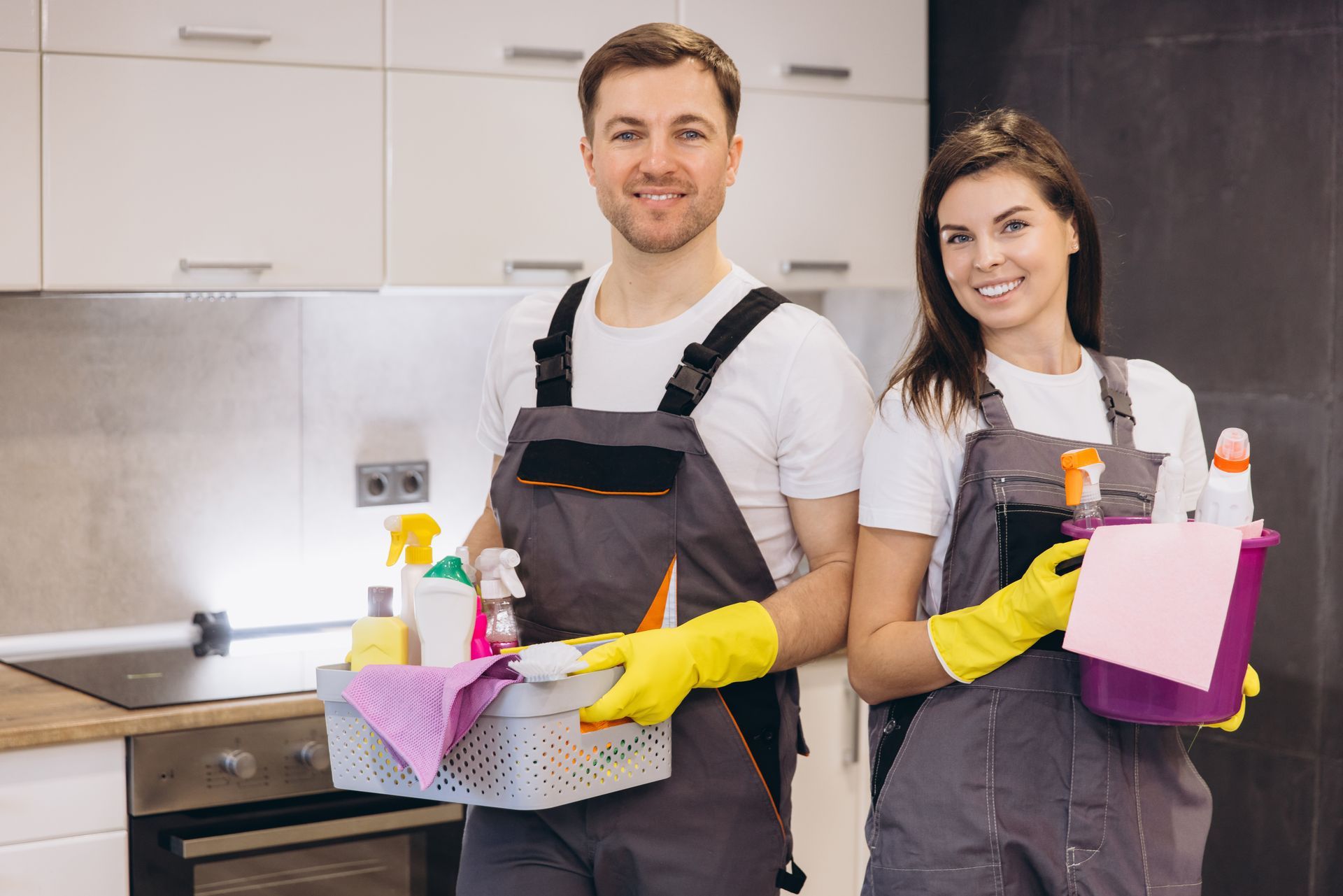 Two movers packing office boxes; one carries a box, the other unpacks a laptop on a desk.