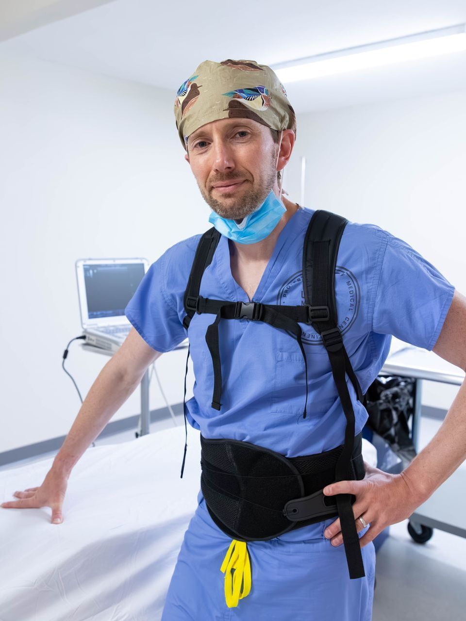 A surgeon wearing a backpack is standing in an operating room