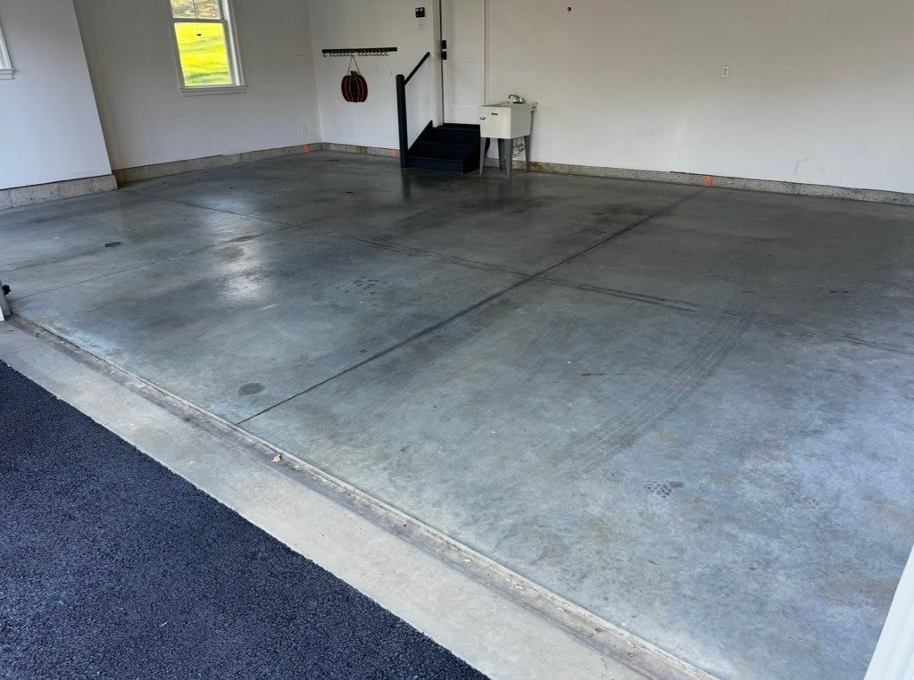 Empty garage with concrete floor, white walls, and a small window.
