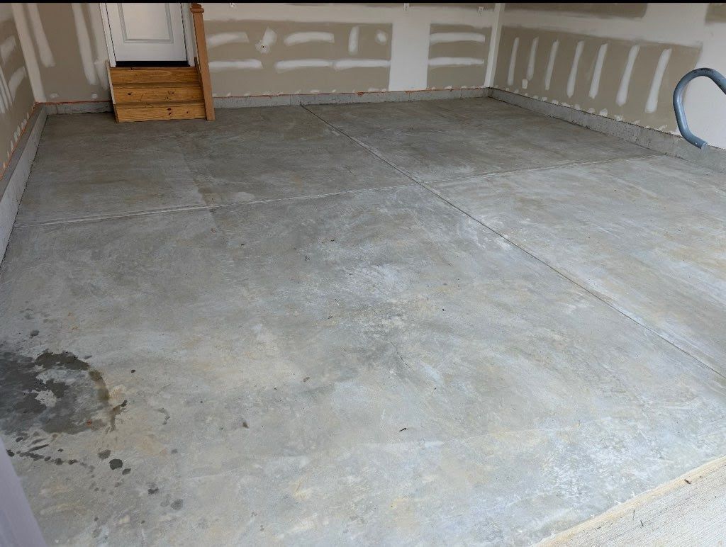 A concrete garage floor with visible cracks, leading to a wooden staircase and door.