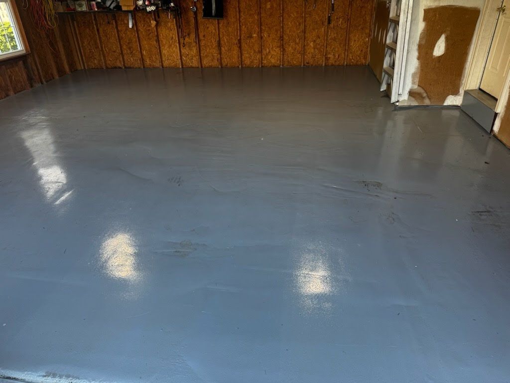 Grey painted garage floor, reflective surface, unfinished walls.