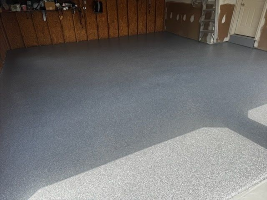 Gray epoxy-coated garage floor with light reflection; garage interior.