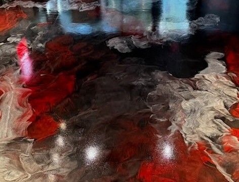 Abstract epoxy floor with swirling red, black, and white patterns, reflective and glossy.