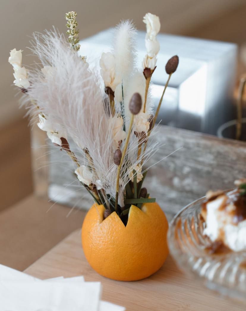 An orange with flowers in it on a table