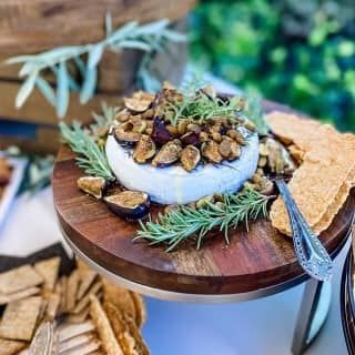 A wooden cutting board topped with a piece of cheese and nuts.
