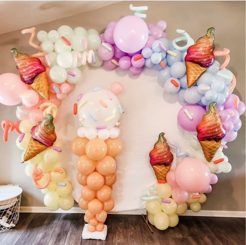 A wall decorated with balloons and ice cream cones