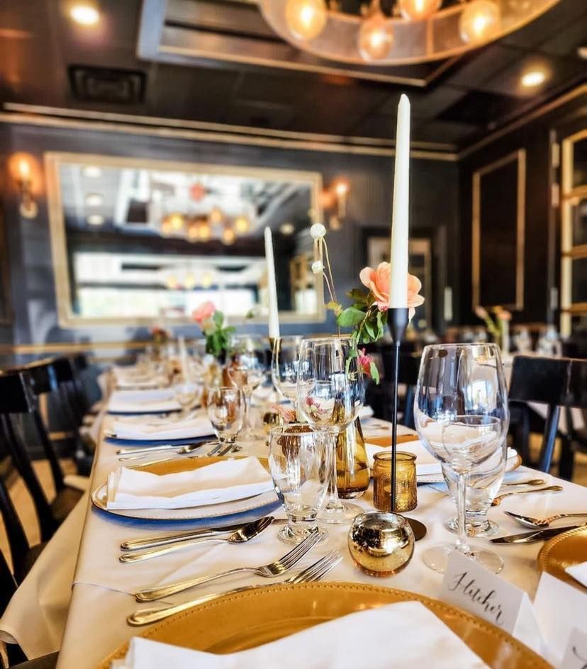 A long table in a restaurant with plates and candles