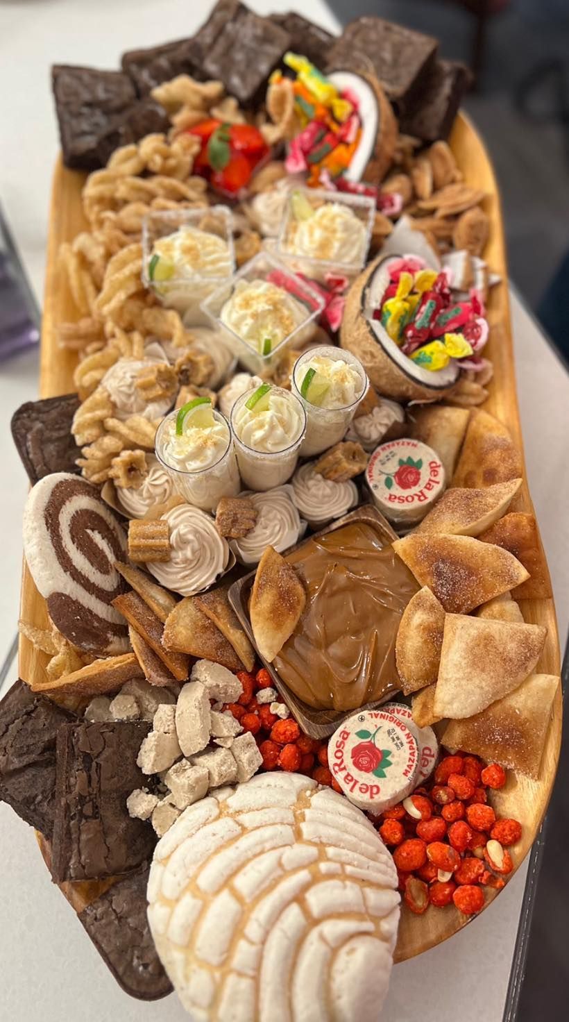 A wooden tray filled with a variety of desserts and candy.