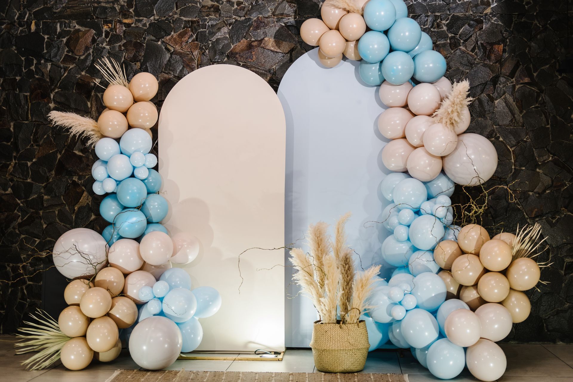 A wall decorated with balloons and pampas grass for a baby shower.