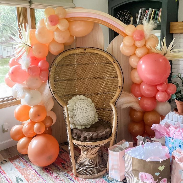 A wicker chair is sitting in front of a balloon arch.