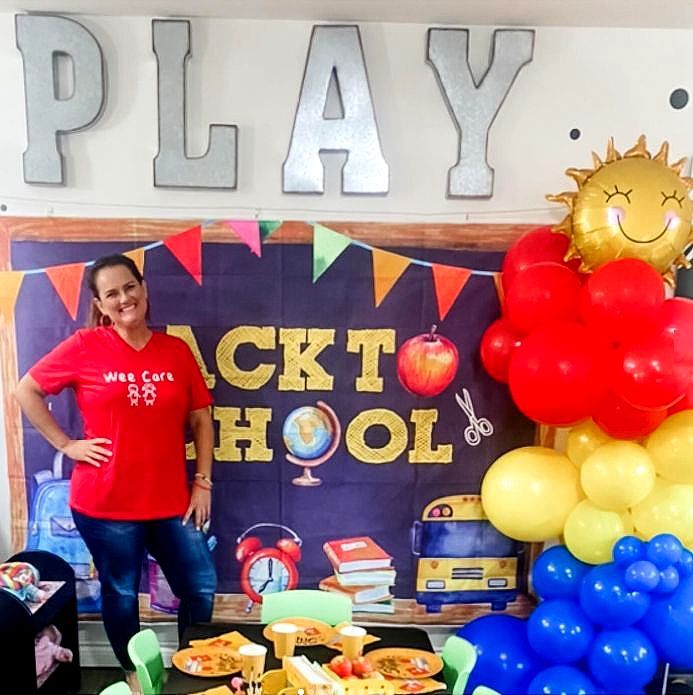 A woman in a red shirt stands in front of a play sign