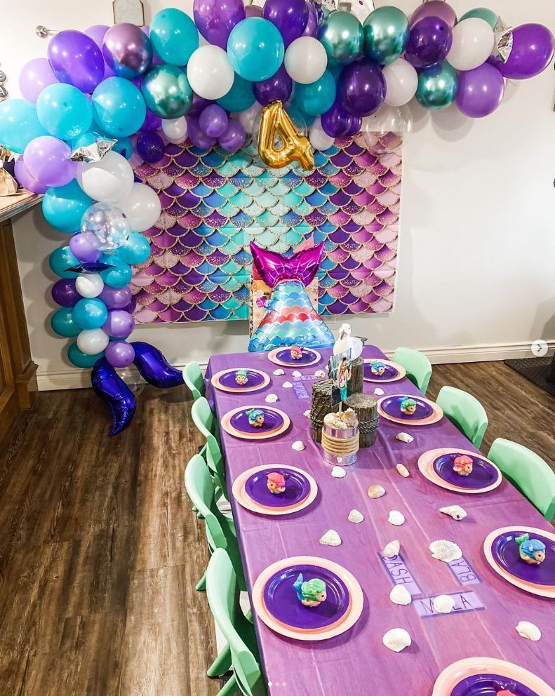 A table with plates and balloons on it for a mermaid birthday party.