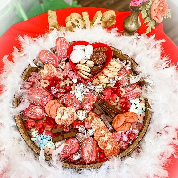 A wooden tray filled with candy and feathers on a table.