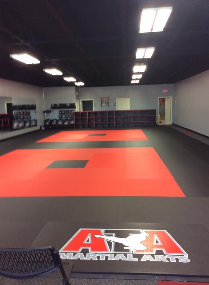 A martial arts gym with a red and black mat