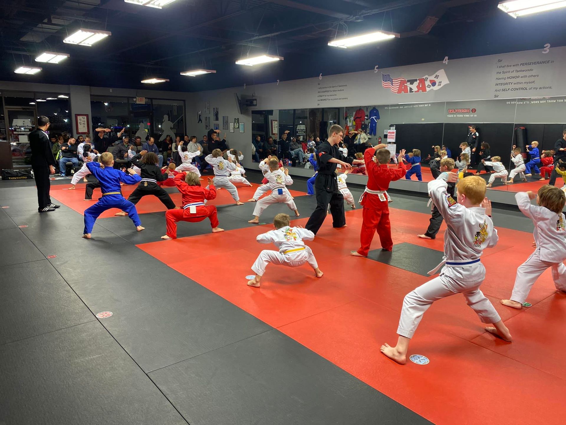 A group of children are practicing martial arts in a gym.