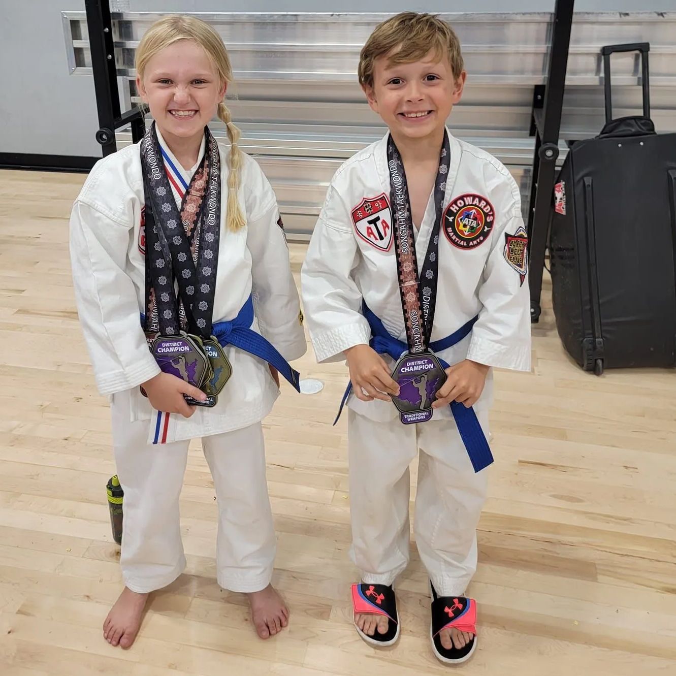 A boy and a girl are standing next to each other holding medals.